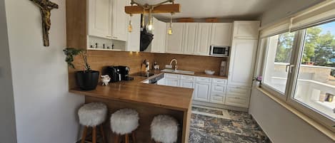 Una cocina moderna con una isla de madera, taburetes de bar, una lámpara colgante y vistas a través de una ventana.