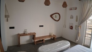 A room with a wooden bench, a bed with a mattress, and a window with curtains. - Mahika Valley Stay (Jaipur)