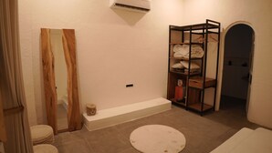 A bathroom with a wooden vanity, a round rug, a towel rack, and a wall-mounted air conditioner. - Mahika Valley Stay (Jaipur)