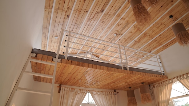 A room with a wooden ceiling, a white balcony railing, and a window with curtains. - Mahika Valley Stay (Jaipur)