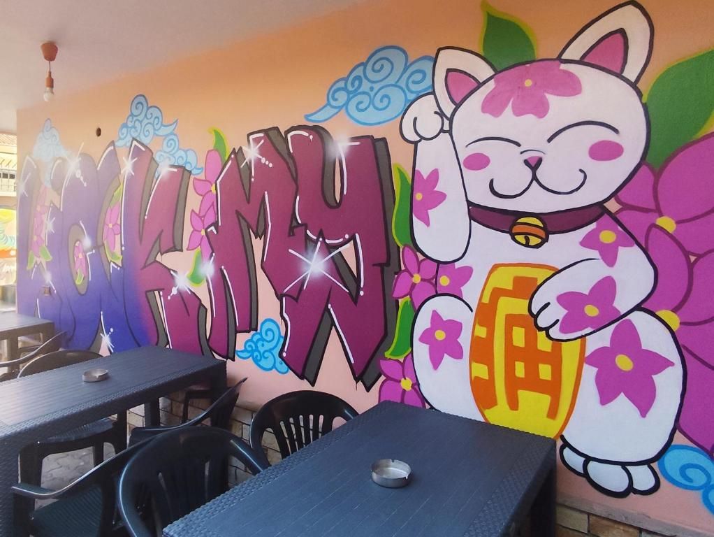 Un restaurante con un mural colorido que muestra un gato y la palabra 'MOKINYU' en letras grandes.