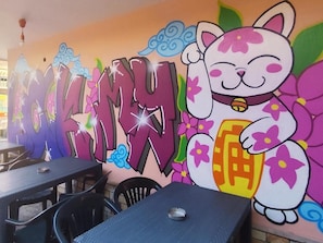 A restaurant with a colorful mural featuring a cat and the word 'MOKINYU' in large letters.