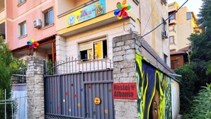 Albergue com uma placa colorida, entrada com portão e um mural na parede.