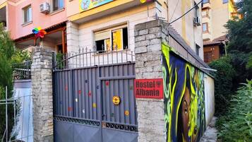 Ostello con un cartello colorato, un ingresso chiuso da cancello e un murale sulla parete.