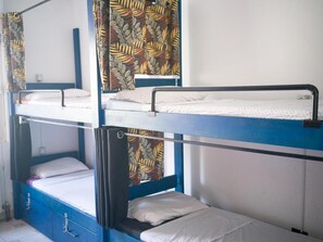 A bunk bed room with curtains, a window, and a wall-mounted shelf.