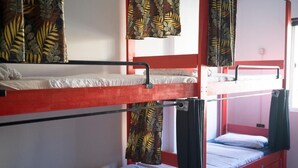 Quarto com beliche de estrutura vermelha, cama inferior com colchão branco e cama superior com colchão preto.