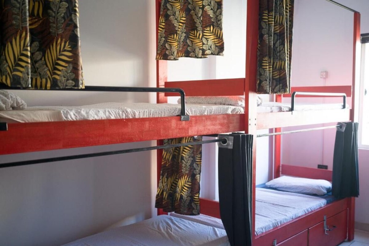 Camera con letto a castello, struttura rossa, un letto inferiore con materasso bianco e un letto superiore con materasso nero.