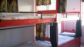 Een slaapkamer met stapelbed, een rood frame, een onderste bed met een witte matras en een bovenste bed met een zwarte matras.