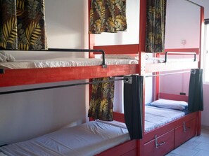 Camera con letto a castello, struttura rossa, un letto inferiore con materasso bianco e un letto superiore con materasso nero.