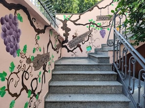 A staircase with a wall mural depicting a vineyard and labeled areas such as 'Living Room Terrace' and 'Kitchen.' - Villa Villekulla Tirana  (Tirana)