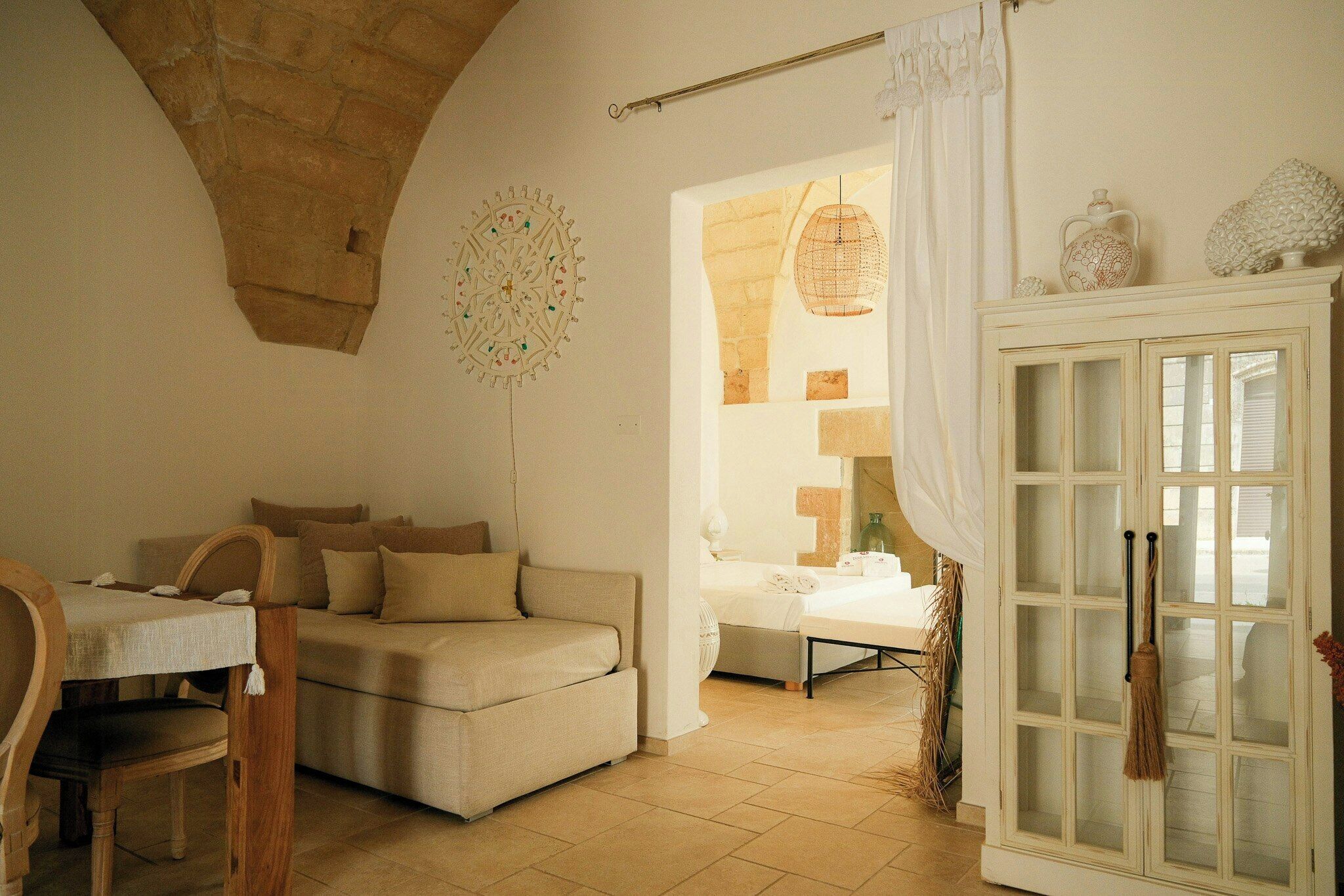 Una habitación acogedora con un sofá, una mesa y un aparador con puertas de cristal.