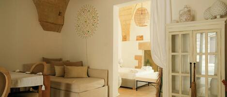 Una habitación acogedora con un sofá, una mesa y un aparador con puertas de cristal.