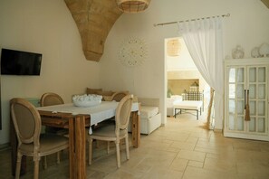 Ein Essbereich mit Holztisch und Stühlen, einer weißen Tischdecke und einer Decke mit einem einzigartigen Steinmuster.