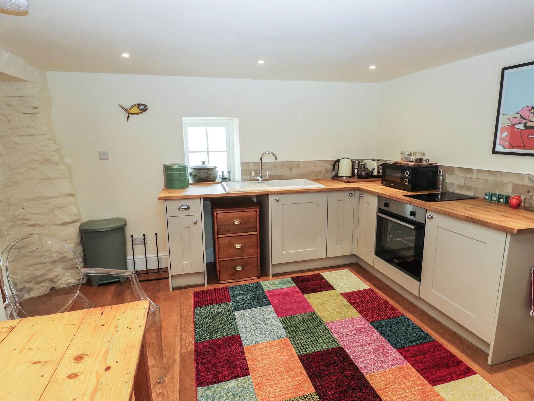 A compact kitchen with a wooden countertop, a sink, a stove, and cabinets.