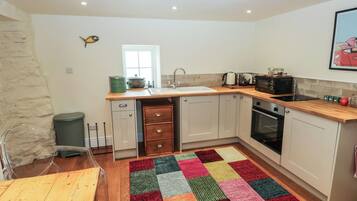 A compact kitchen with a wooden countertop, a sink, a stove, and cabinets.