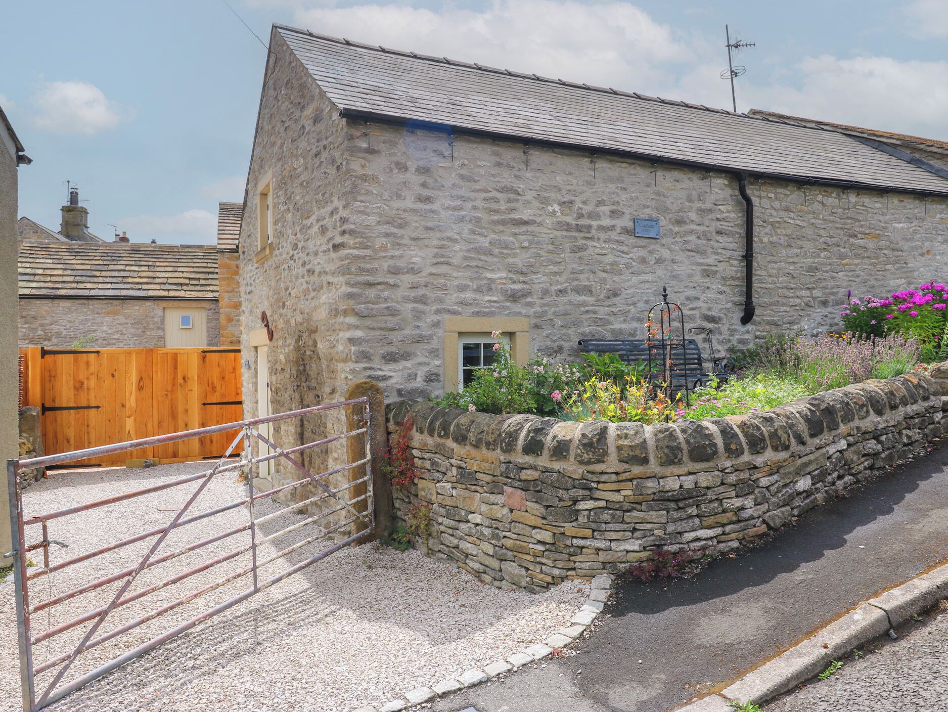 A stone building with a metal gate and a flower bed.