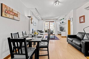 A modern living room with a dining area, a black leather sofa, and a dining table set for four. - Sea Views Apartment with Terrace and Pools (Puerto de la Duquesa)
