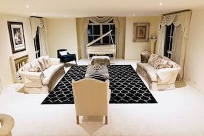 A spacious living room with two sofas, a piano, and a patterned rug.