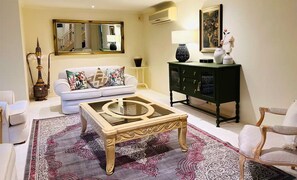 A living room with a sofa, a coffee table, a cabinet, and a mirror. - Sarovar Holidays: A luxurious retreat in the heart of Traralgon (Traralgon)
