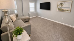A living room with a grey sofa, a lamp, a flat-screen TV, and a framed picture on the wall. - Beach Casita 1-bedroom Apt by Boardwalk and Beach (Ocean City)