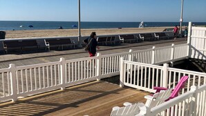 A wooden deck with white railings, beach chairs, and a view of the ocean. - Beach Casita 1-bedroom Apt by Boardwalk and Beach (Ocean City)