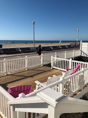 A wooden deck with white railings, beach chairs, and a view of the ocean. - Beach Casita 1-bedroom Apt by Boardwalk and Beach (Ocean City)
