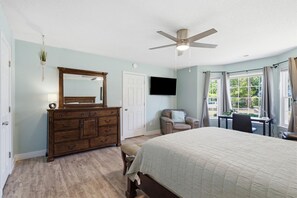 Un dormitorio con cama, cómoda, silla, escritorio y ventilador de techo.