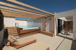Terraza en la azotea con piscina, deck de madera y zona de estar al aire libre.
