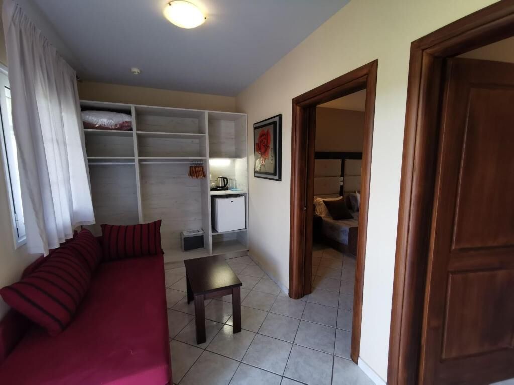 A room with a red sofa, a small table, a white cabinet, and a wooden door.