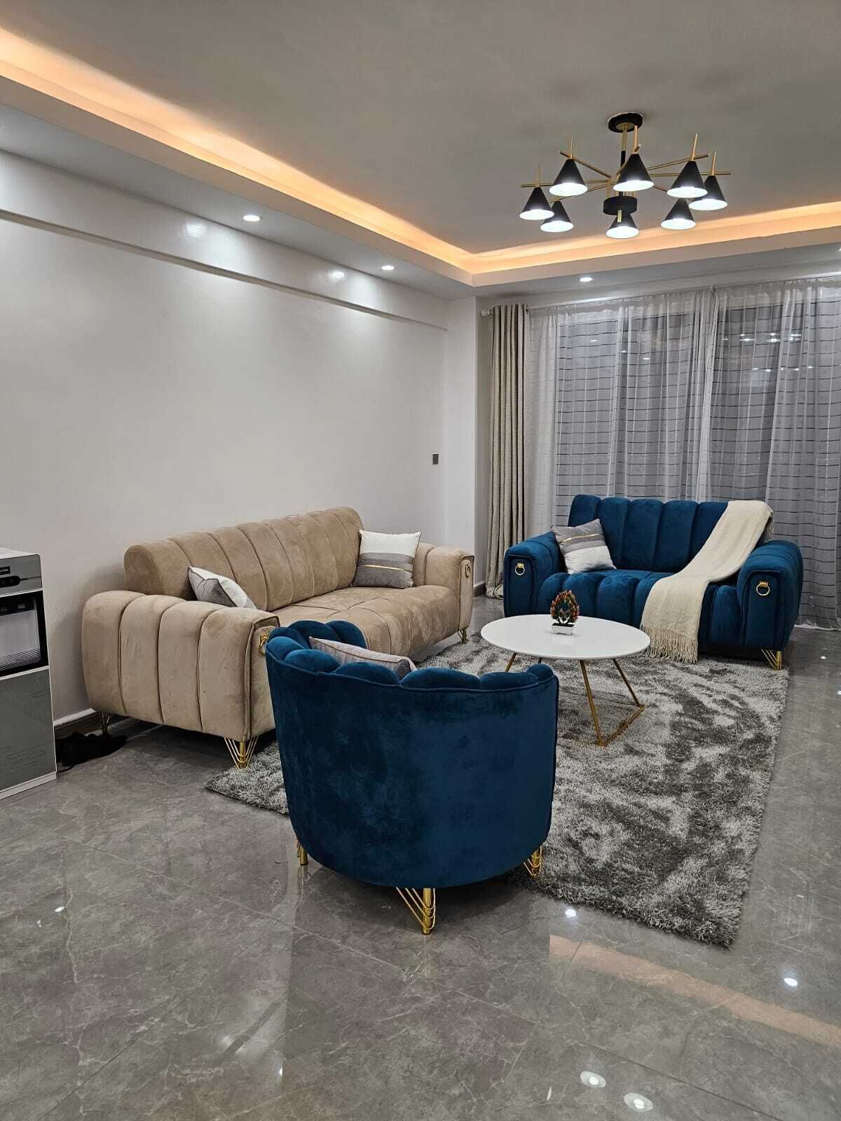 A modern living room with a beige sofa, a blue armchair, and a white coffee table.