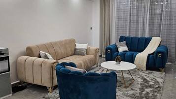 A modern living room with a beige sofa, a blue armchair, and a white coffee table.