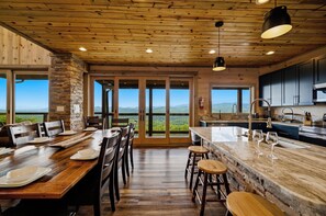 A spacious kitchen with a large island, wooden ceiling, and large windows offering a view of the mountains. - 6 Bedrooms with Mini Golf - Indoor Waterfall Pool - Awesome Views! (Sevierville)