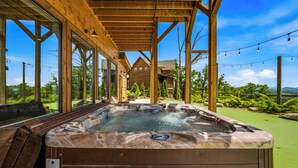Un bain à remous installé sous une pergola en bois, offrant une vue sur un paysage montagneux.