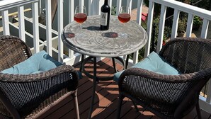 Eine Terrasse mit Korbstühlen und einem Tisch, mit Blick auf einen Yachthafen mit Booten und Häusern.