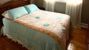 Ein Schlafzimmer mit einem Bett, einem Deckenventilator, einem Fenster mit Vorhängen und einem Bild an der Wand.