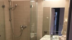 Un baño moderno con ducha envuelta en vidrio, lavamanos con espejo e inodoro.