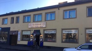 Un edificio con un cartel que indica un restaurante llamado 'Wiener Küche - Pizza' y dos letreros que dicen 'Gastgarten'.