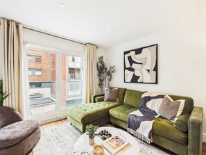 Ein modernes Wohnzimmer mit einem grünen Sofa, einem Couchtisch und einem großen Fenster.
