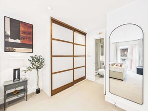 A modern interior with a sliding door, a large mirror, and a framed artwork on the wall. - Comfy Central 2 Bedroom Westminster Apartment (Greater London)