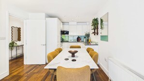 A modern kitchen with white cabinets, a dining table with chairs, and a white radiator.