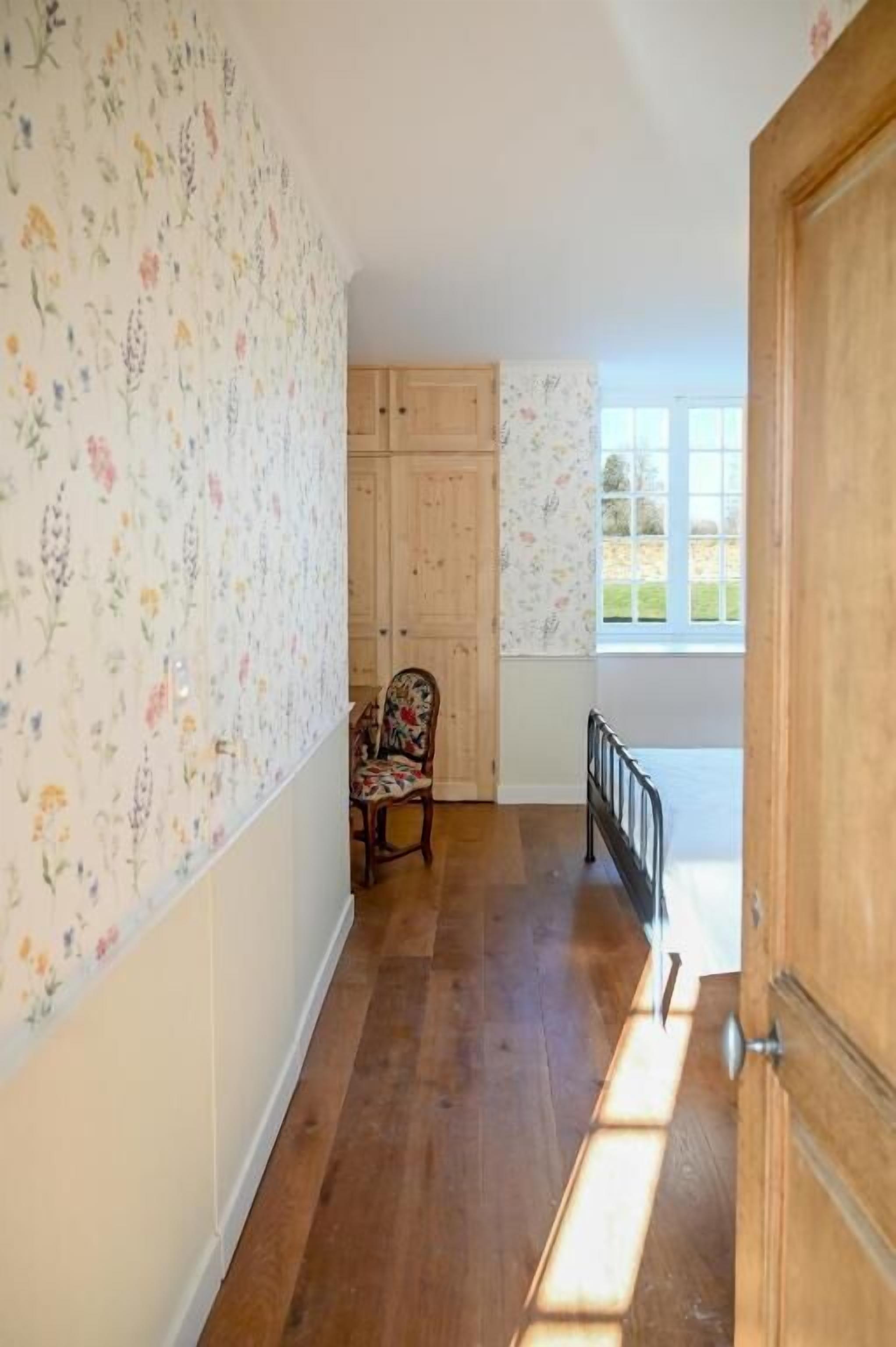 A hallway with wooden flooring, a chair, and a wooden door.