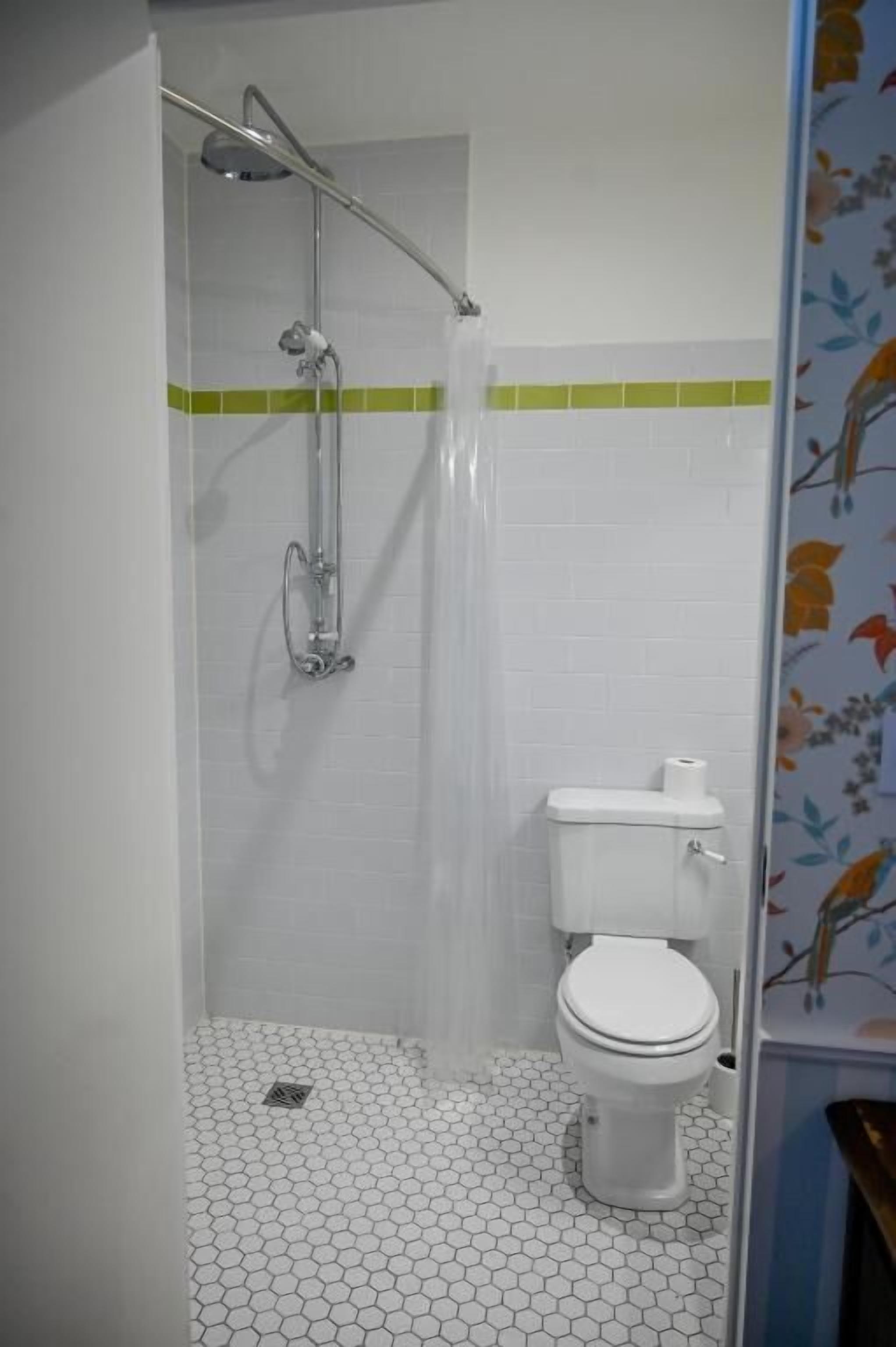 A bathroom with a shower, toilet, and a tiled floor.