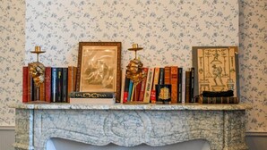 A fireplace mantel with a marble surround, flanked by a floral-patterned wallpaper. - Château de Saint Clair (Saint-Clair-sur-l'Elle)