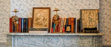 A fireplace mantel with a marble surround, flanked by a floral-patterned wallpaper.