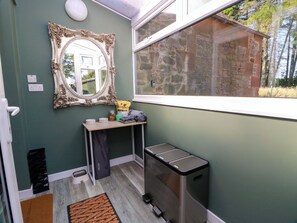 A bathroom with a mirror, a window, a sink, and a trash bin.