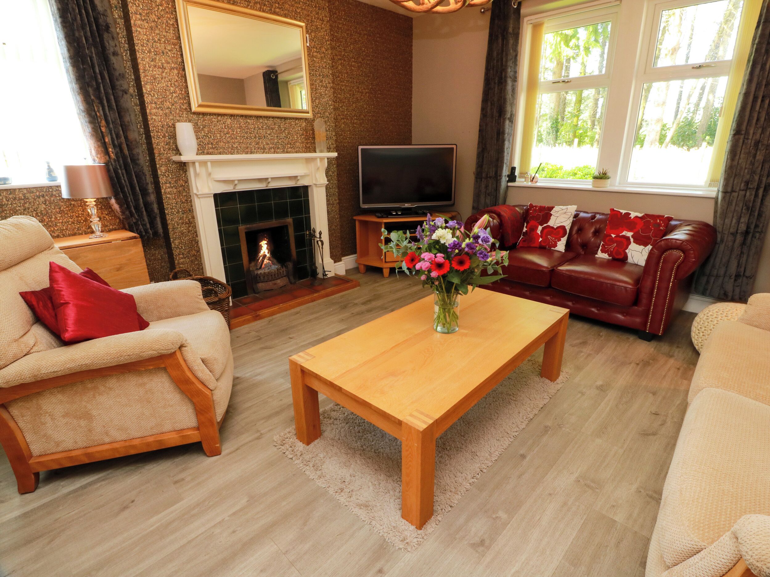 A living room with a fireplace, a television, a sofa, and a coffee table with a floral arrangement.