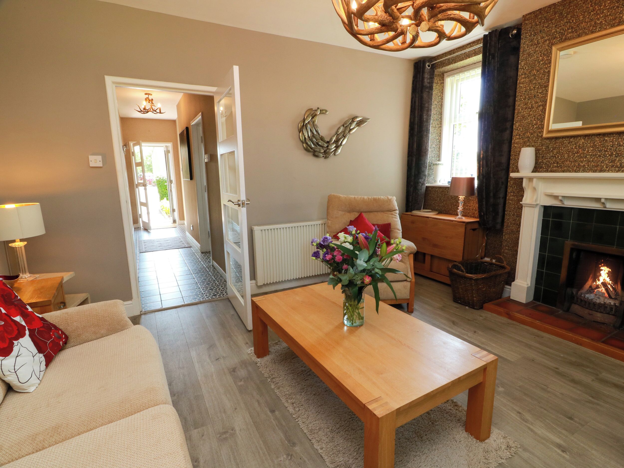 A living room with a sofa, a coffee table, a fireplace, and a hallway leading to another room.
