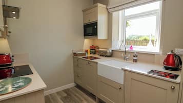 Una cocina moderna con microondas integrado, un hervidor rojo y una ventana con vistas a la vegetación.