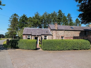 A two-story stone building with a paved driveway and a well-maintained hedge. - Waterside Lodge (Lockerbie)