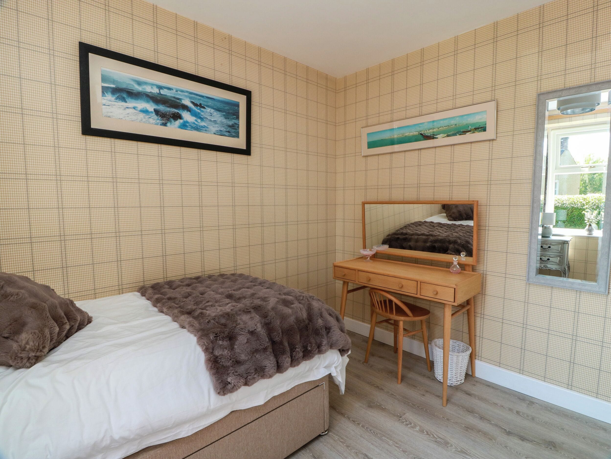 Un dormitorio con cama, un escritorio y dos cuadros en la pared.